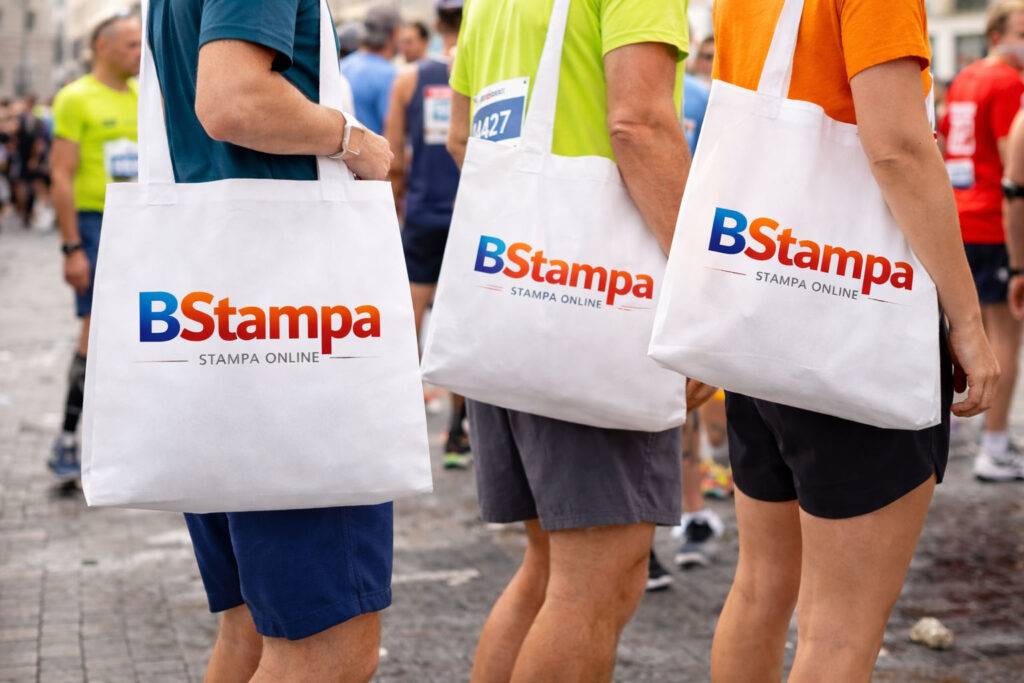 Partecipanti a una maratona con shopper in TNT personalizzate con i loghi degli sponsor, pubblicità mobile durante l'evento.